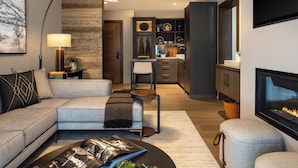 A modern living room with a sofa, coffee table, fireplace, and kitchen in the background. - Hotel Jackson (Jackson)