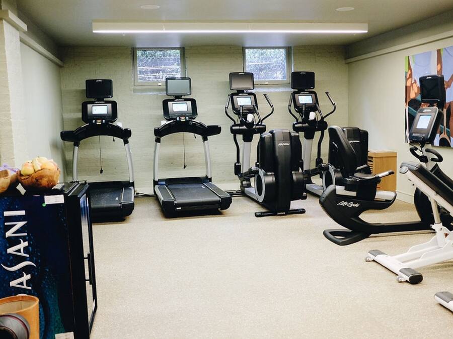 Un gimnasio con diferentes máquinas de cardio, una caminadora, una elíptica y una bicicleta estática.