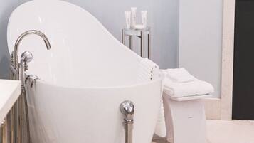 Une salle de bain moderne avec une baignoire sur pieds, des toilettes et une petite table sur laquelle sont posés des articles de toilette.