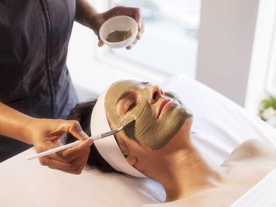 A person receiving a facial treatment with a mask applied to their face.
