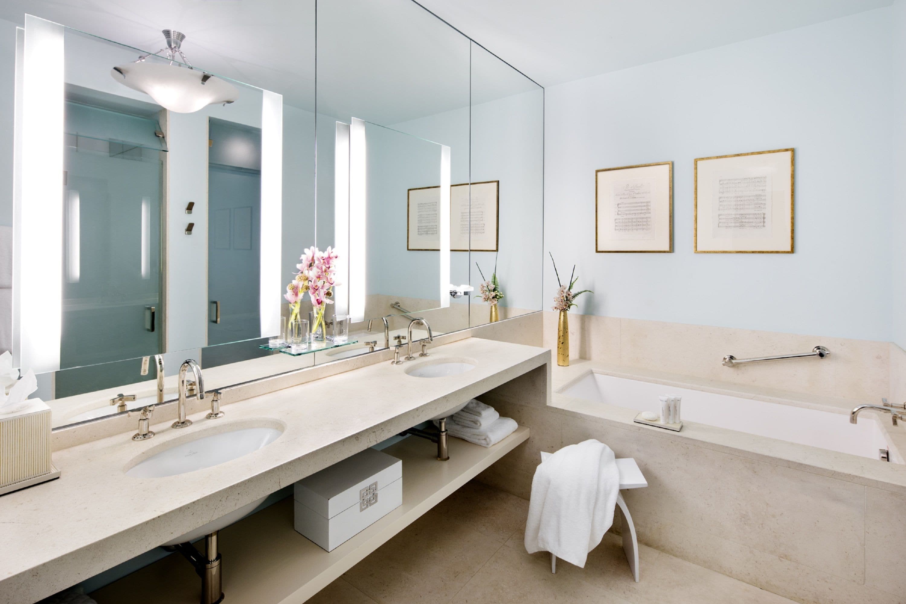Un baño moderno con dos lavamanos, un espejo grande y una bañera.
