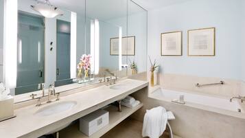Un baño moderno con dos lavamanos, un espejo grande y una bañera.