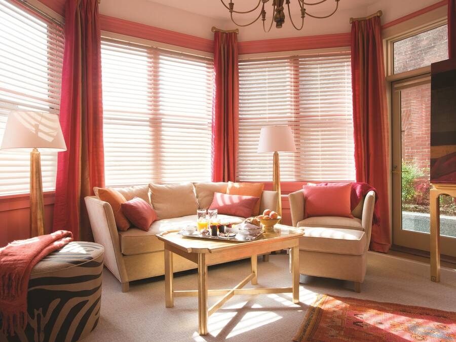 A cozy room with a sofa, a table with breakfast items, and a window with blinds.