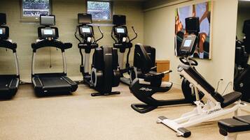 Een sportschool met loopbanden, elliptische trainers en een hometrainer, uitgerust met digitale schermen.