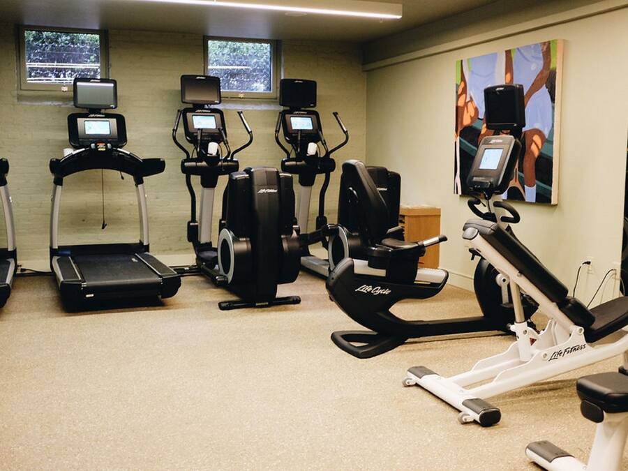 Een sportschool met loopbanden, elliptische trainers en een hometrainer, uitgerust met digitale schermen.