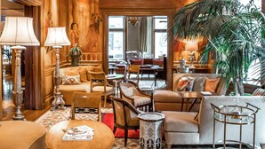 A luxurious lobby with a high ceiling, ornate chandeliers, plush seating, and a large plant. - The Ivy Hotel (Baltimore)