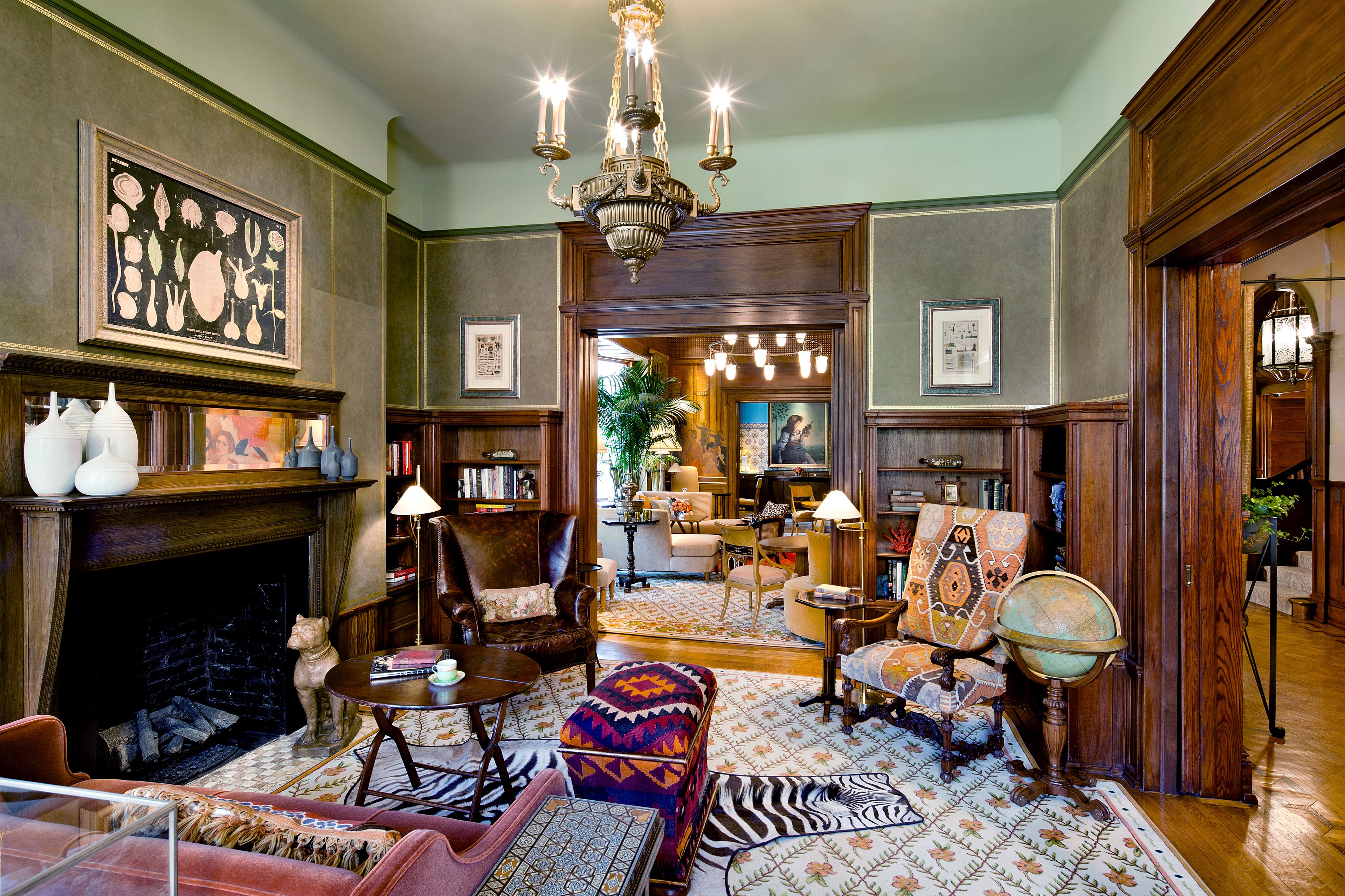A traditional living room with a fireplace, a globe, and a variety of seating options.