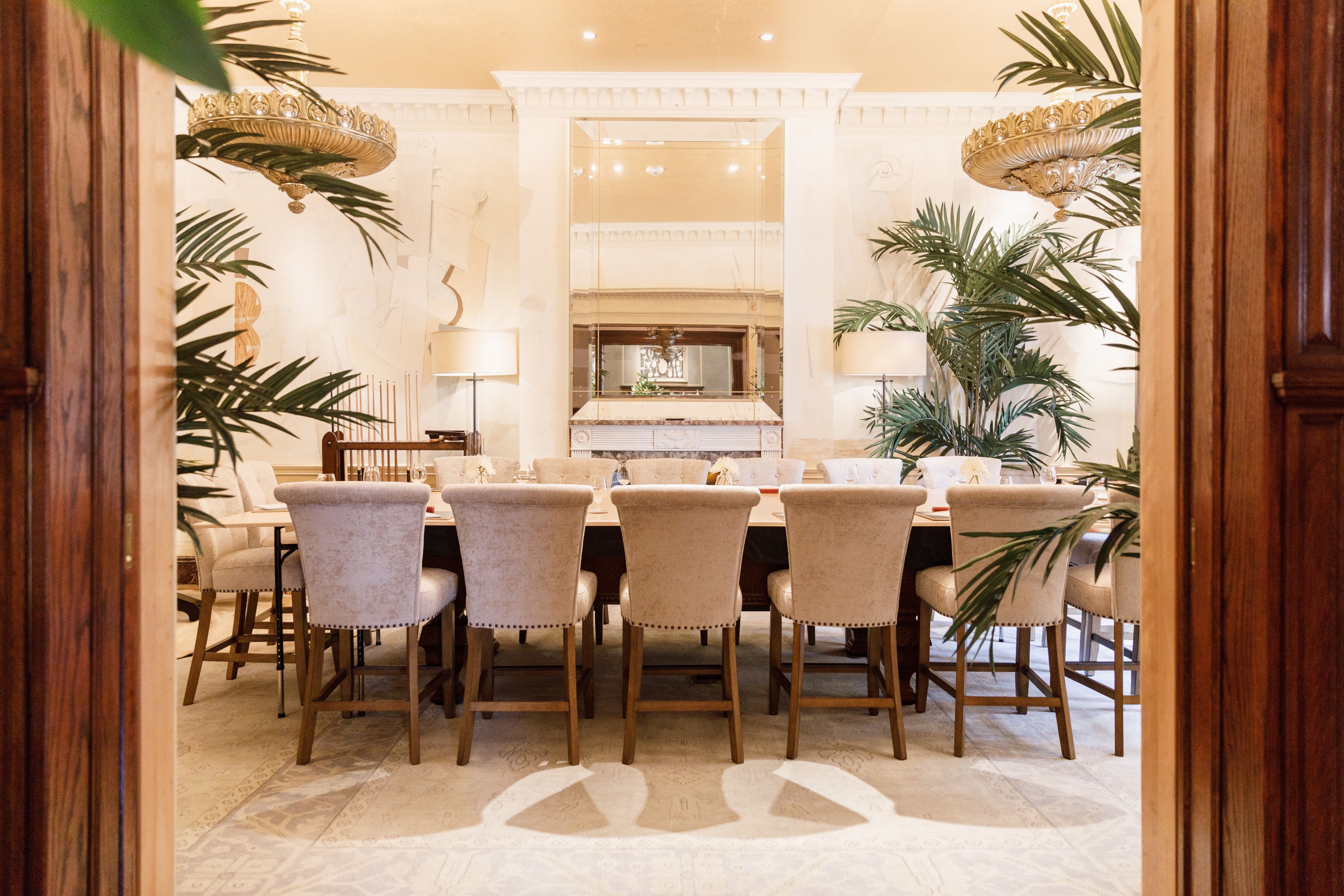 A formal dining room with a marble table, upholstered chairs, and a chandelier.