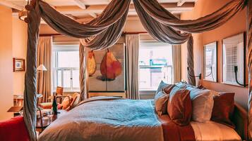 A bedroom with a canopy bed, a desk with a chair, and a large window with curtains.