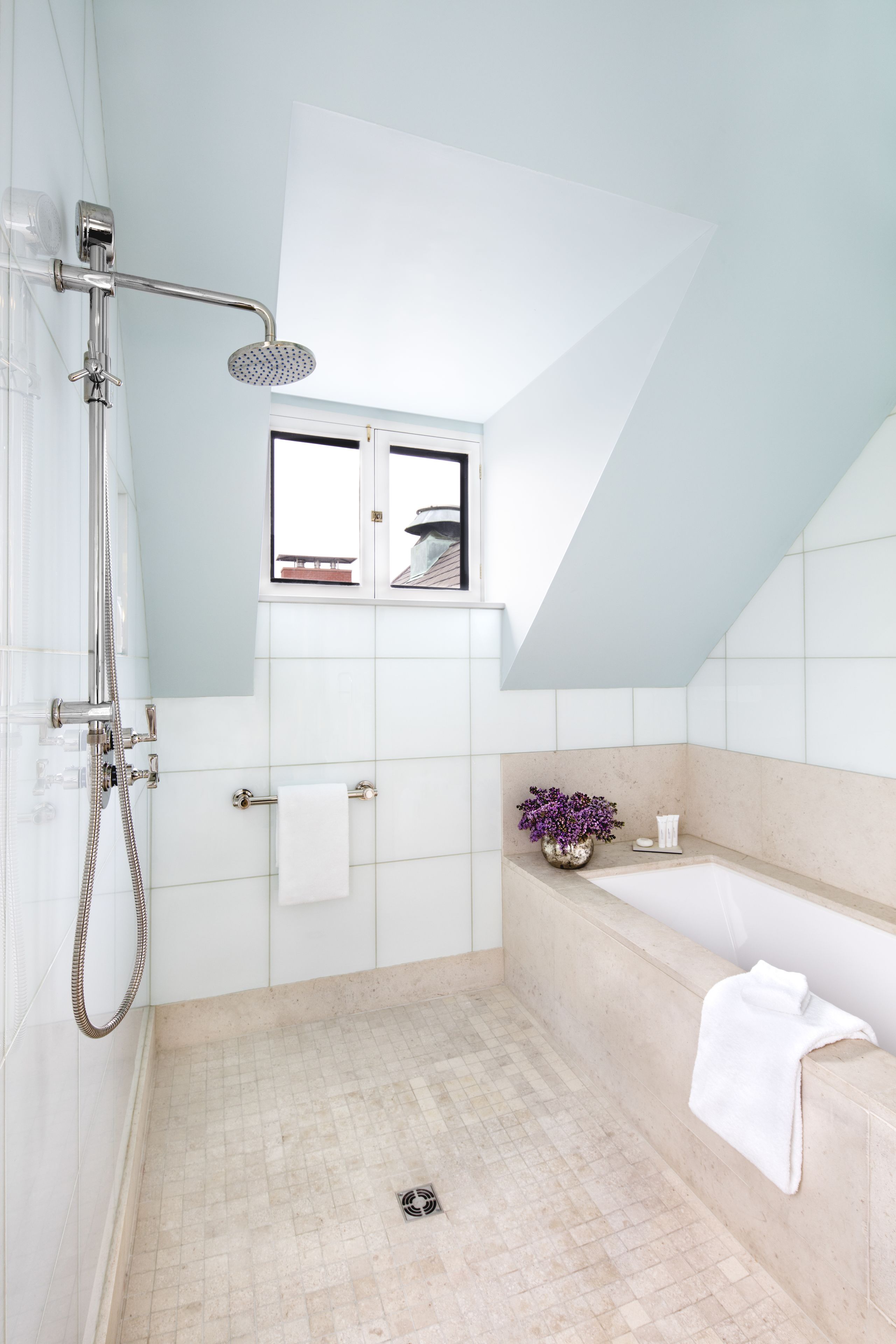A modern bathroom with a walk-in shower, a bathtub, and a window above the sink.