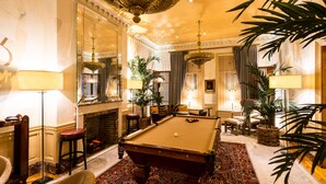A billiards room with a pool table, chairs, and a fireplace. - The Ivy Hotel (Baltimore)