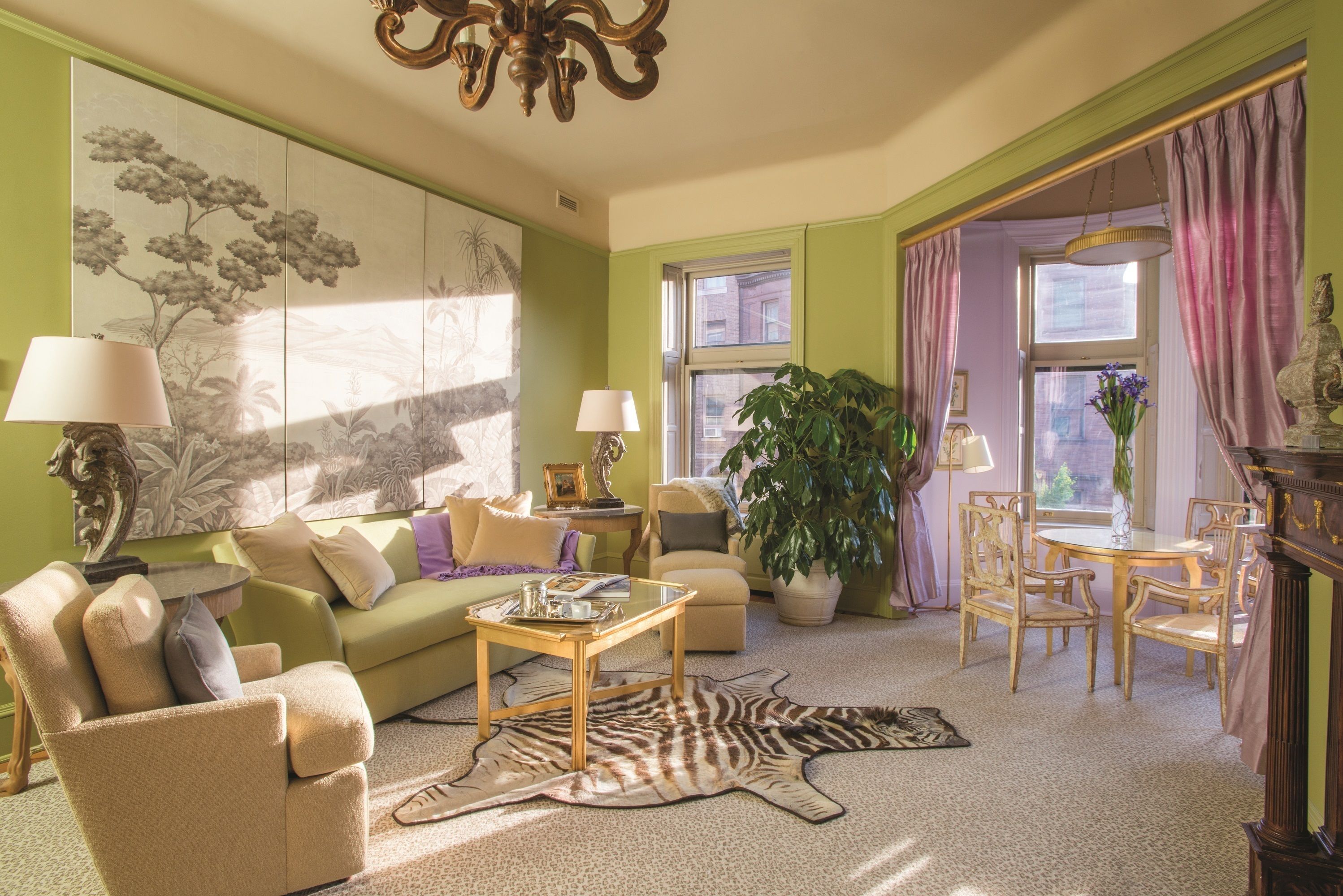 A living room with a green wall, a zebra print rug, a sofa, a coffee table, and a dining area with chairs and a table.