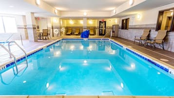 Un área de piscina de hotel con una piscina limpia, sillas de descanso y un espacio de estar con mesas y sillas.
