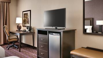 Une chambre d’hôtel comprenant un lit, un bureau avec une télévision, une chaise, une commode et un miroir.