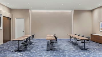 A conference room with a long table and chairs, carpeted floor, and recessed ceiling lights.