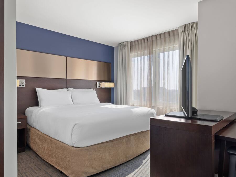 A modern hotel room with a large bed, a desk with a computer, and a TV.