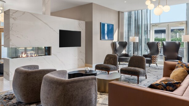 A modern living room with a fireplace, comfortable seating, and large windows. - Residence Inn New York The Bronx At Metro Center Atrium (Bronx)