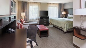A hotel room with a bed, a desk with a computer, a chair, a TV, and a lamp. - Staybridge Suites Canton by IHG (Canton)