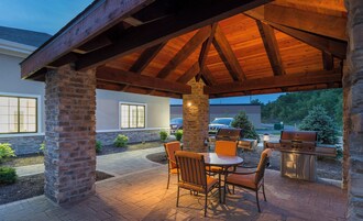 An outdoor patio with a brick column, a wooden pergola, and a grill station.