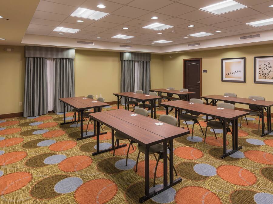 A conference room with multiple tables and chairs, a patterned carpet, and ceiling lights.