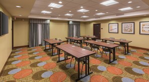 A conference room with multiple tables and chairs, a patterned carpet, and ceiling lights. - Staybridge Suites Canton by IHG (Canton)