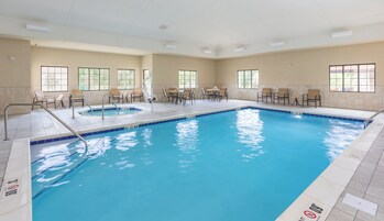 Una piscina cubierta con varias pistas, sillones reclinables y mesas.