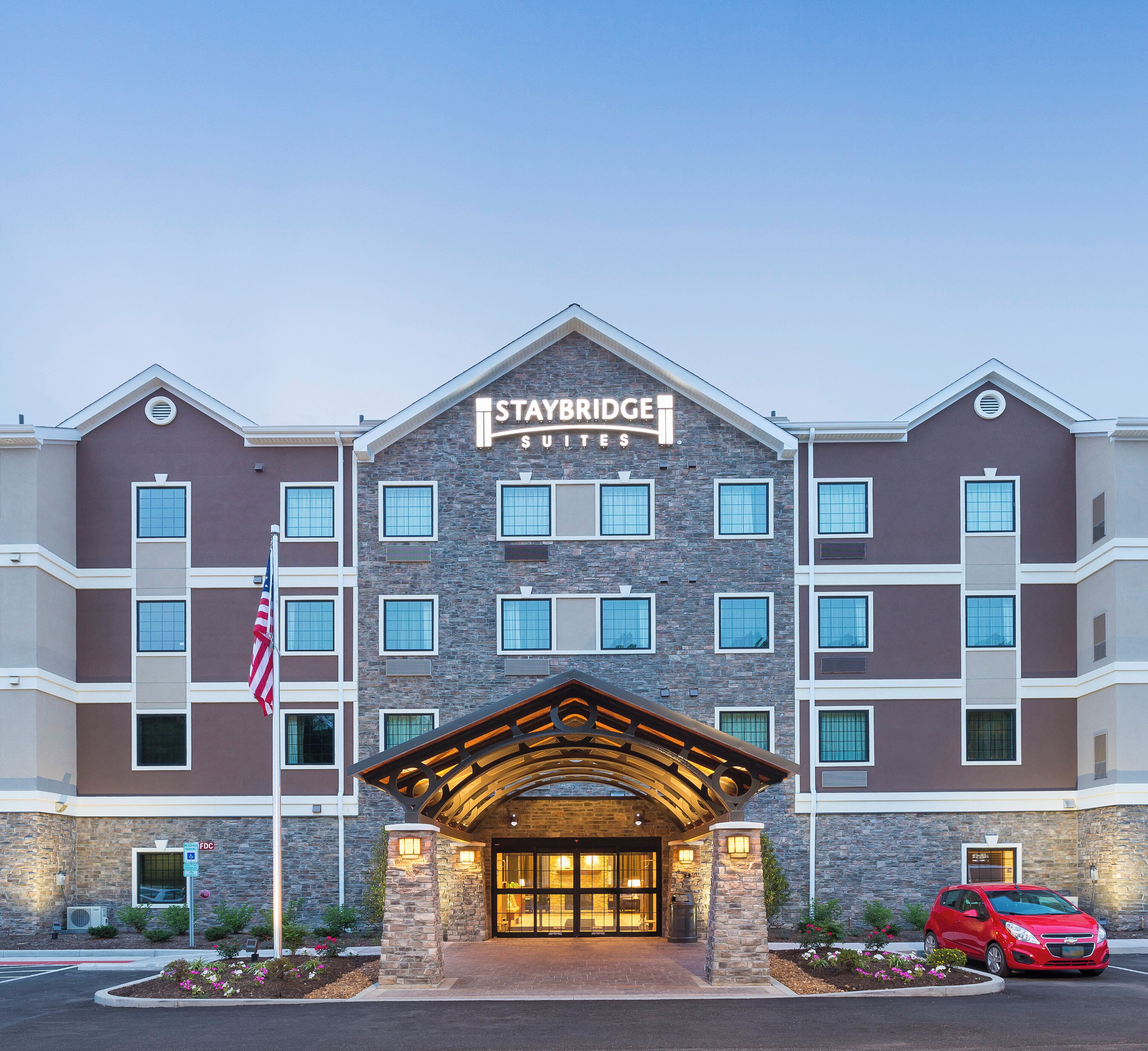 Een Staybridge Suites hotel met een stenen gevel, meerdere ramen en een overdekte ingang.