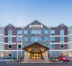 Un hôtel Staybridge Suites doté d’une façade en pierre, de nombreuses fenêtres et d’une entrée abritée.