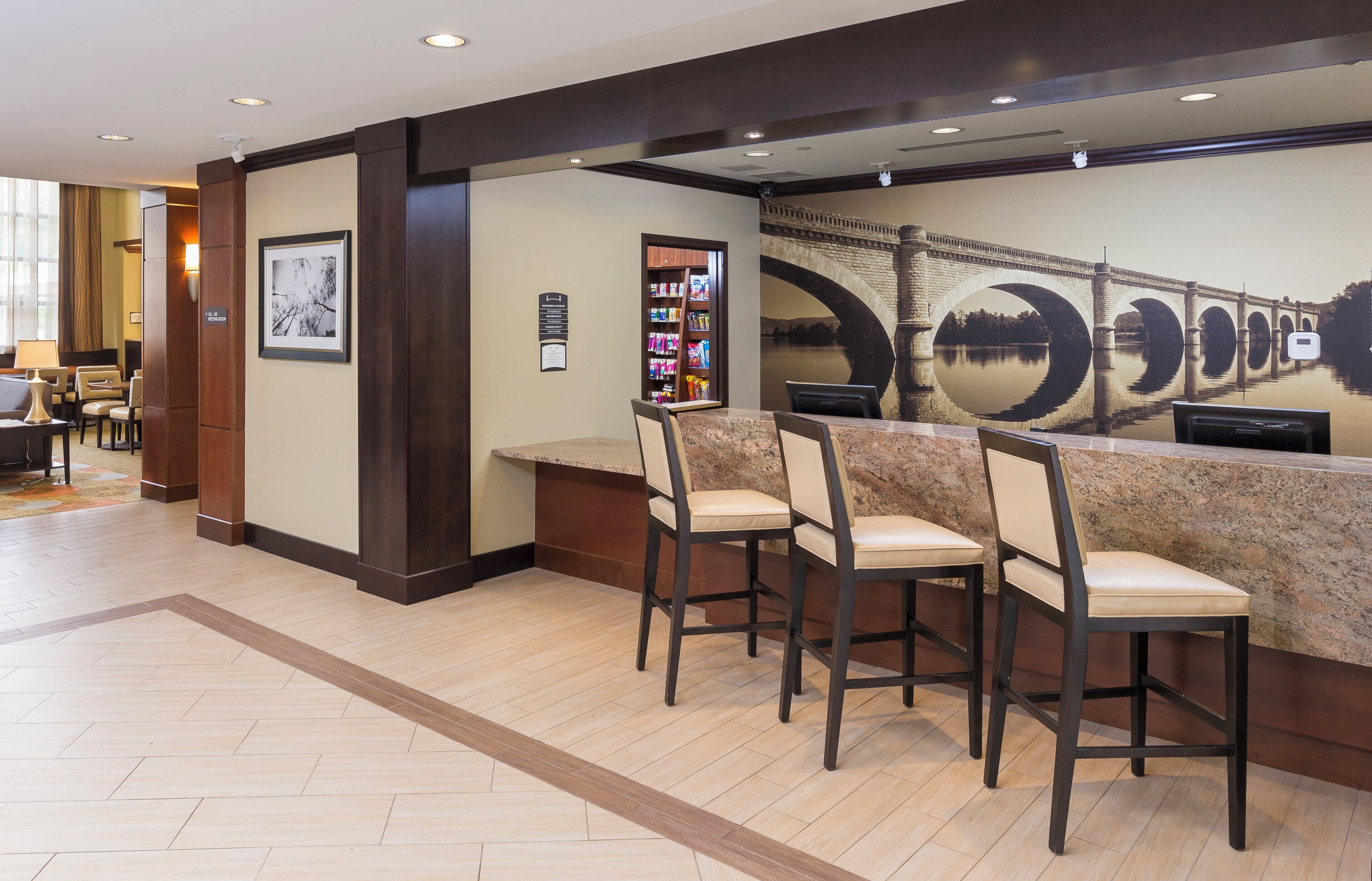 A reception area with a counter, chairs, a framed picture, and a wall with a bridge mural.