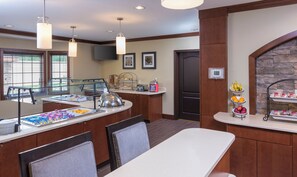 Un espace pour le petit-déjeuner avec un buffet, des tables et des chaises, et un mur décoratif en pierre.