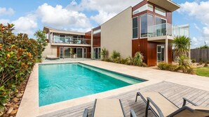 Uma casa moderna com piscina, deck e jardim.