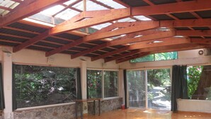 A spacious room with a high ceiling, large windows, and a wooden floor. - Agua Blanca (Jungapeo)