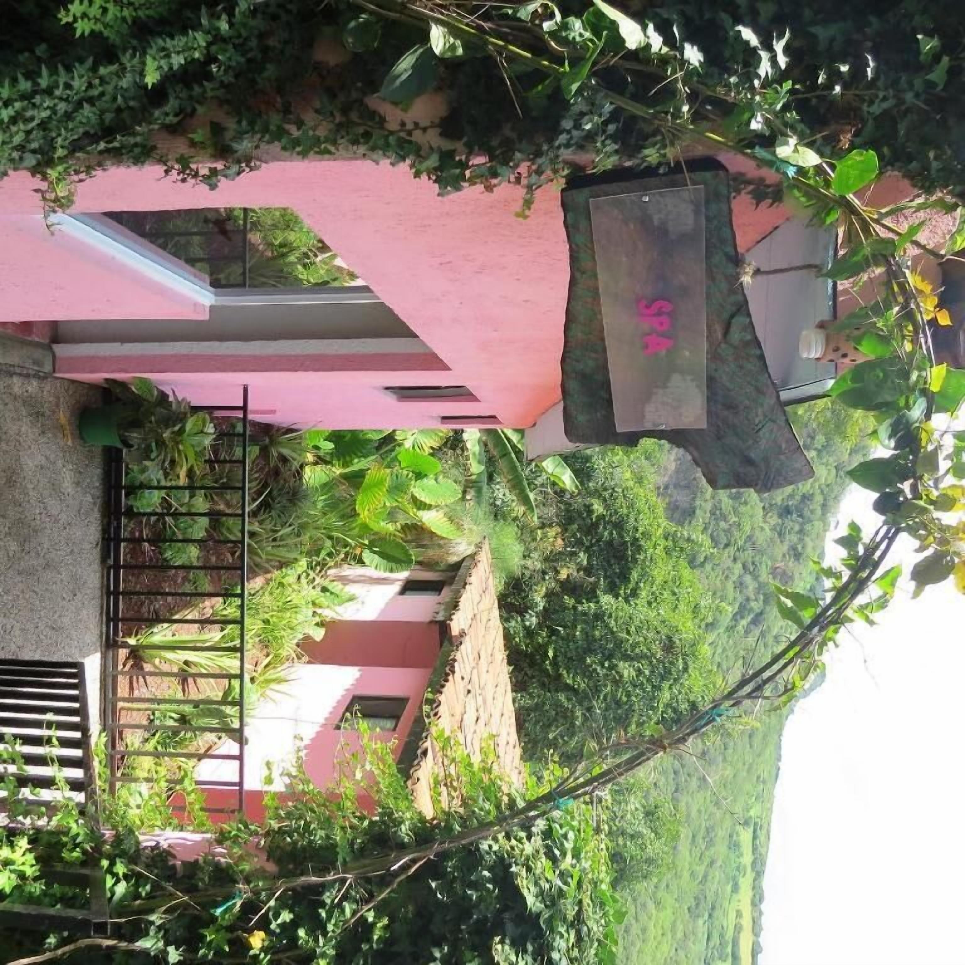 Edifício rosa com portão de metal e uma placa.