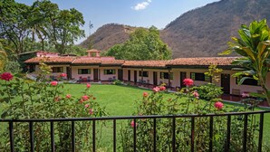 A building with a tiled roof, surrounded by greenery and a mountain in the background. - Agua Blanca (Jungapeo)