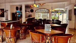 Un interior de restaurante con mobiliario de madera, una mesa de billar y lámparas colgantes.