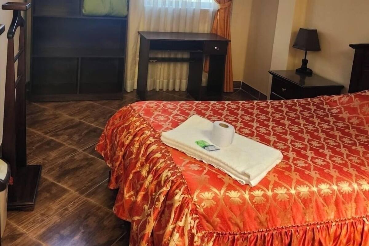 Ein Hotelzimmer mit Bett, Fernseher, Schreibtisch und einem Fenster mit Vorhängen.