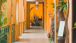 Un couloir aux murs orange, agrémenté d’un lustre et d’un élément décoratif en bois rustique.