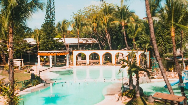 Un espace piscine avec des chaises longues et un coin salon abrité.