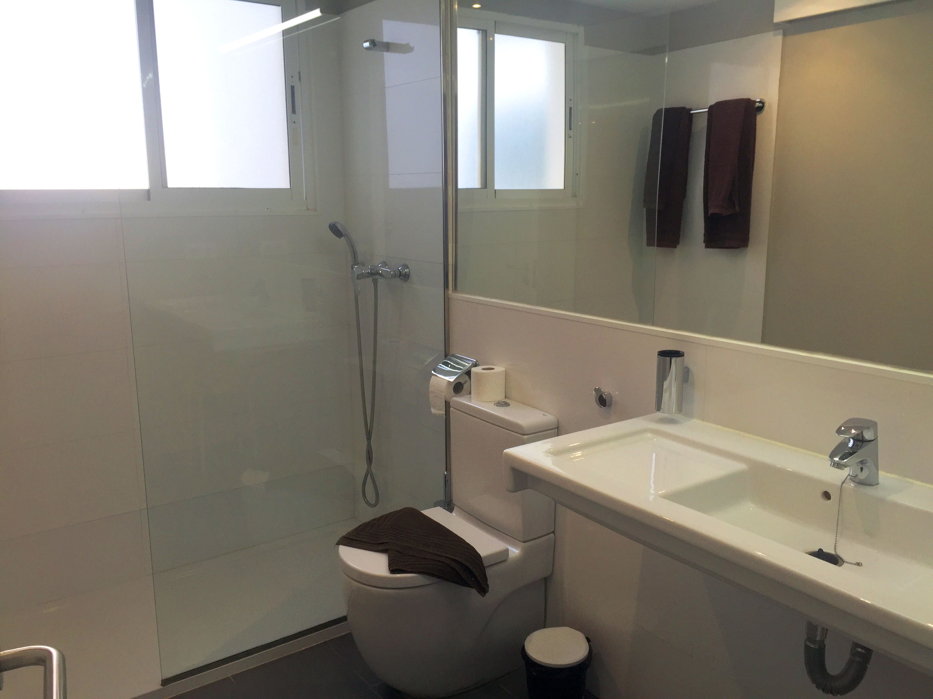 A modern bathroom with a glass-enclosed shower, a toilet, and a sink.