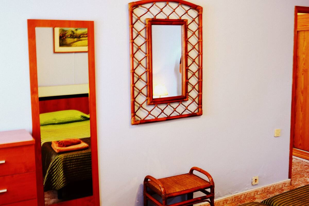 Ein Schlafzimmer mit Bett, Stuhl, Kleiderschrank und Spiegel an der Wand.