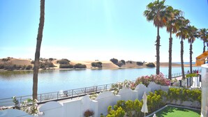 A view of a lake with palm trees and a white building with a balcony overlooking the water.