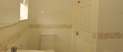 A bathroom with a sink, mirror, toilet, and a door.