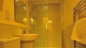 Un baño con ducha envuelta en vidrio, lavamanos e inodoro.
