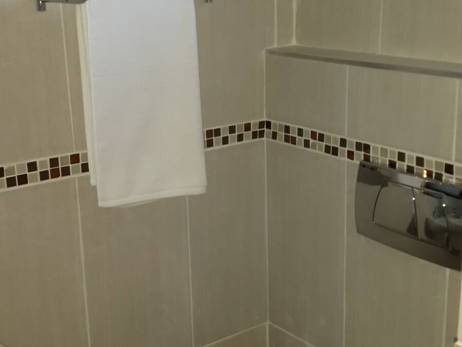 Une salle de bain équipée de toilettes, d’un porte-serviettes et d’un support à papier toilette.
