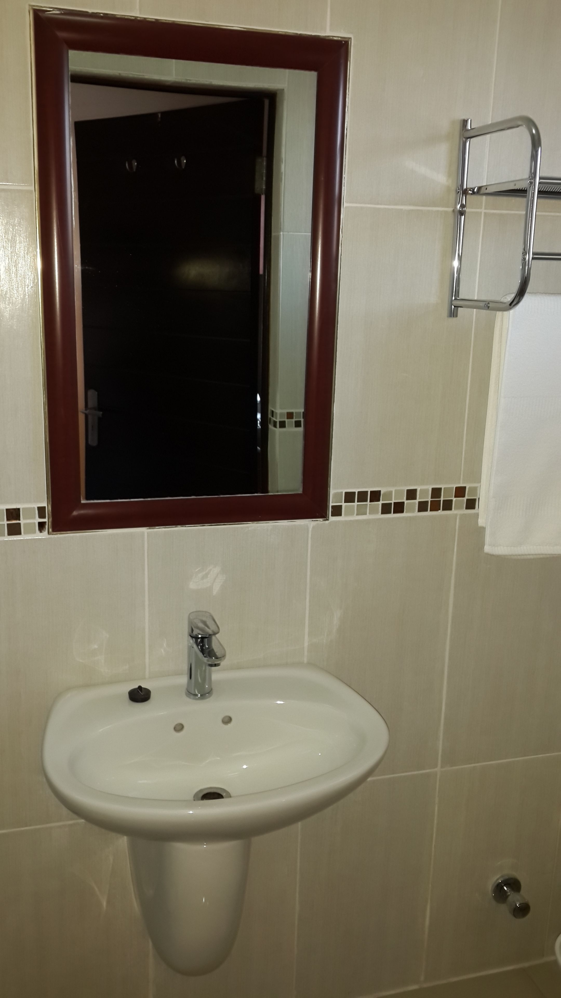 A bathroom with a white sink, a mirror with a wooden frame, and a towel rack.