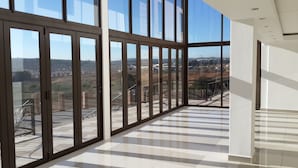 A spacious room with large floor-to-ceiling windows, a checkered floor, and a view of a distant landscape. - Eagle Nest Luxury Accommodation (Roodepoort)