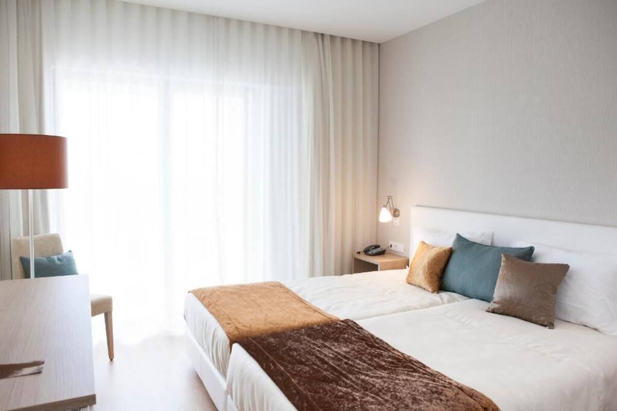 A hotel room with a bed, a desk, and a lamp.
