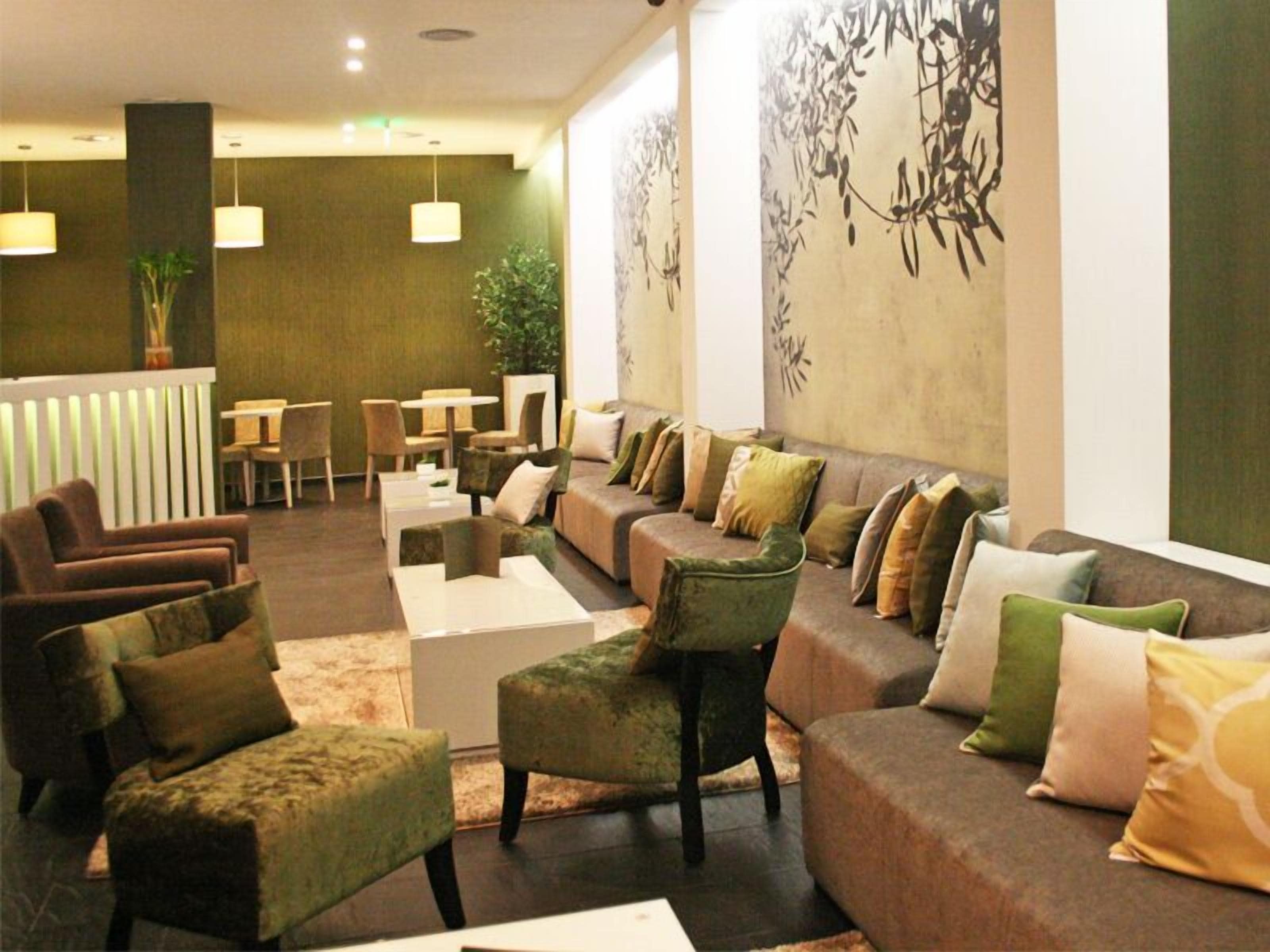 A lobby with a sofa, chairs, tables, and a reception desk.