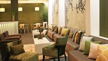 A lobby with a sofa, chairs, tables, and a reception desk.