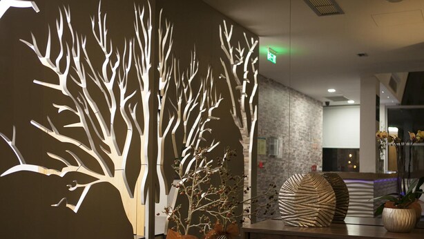A modern lobby with a large tree sculpture, a reception desk, and potted plants. - Flag Hotel Aljustrel (Aljustrel)